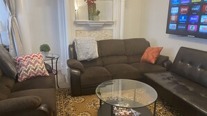 Un salon avec un canapé marron, une table basse en verre et un téléviseur à écran plat fixé au mur.