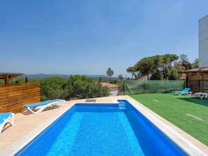 A swimming pool with blue tiles, surrounded by a wooden fence and a green lawn. - Privileged space for a few dream days (Fogars de la Selva)