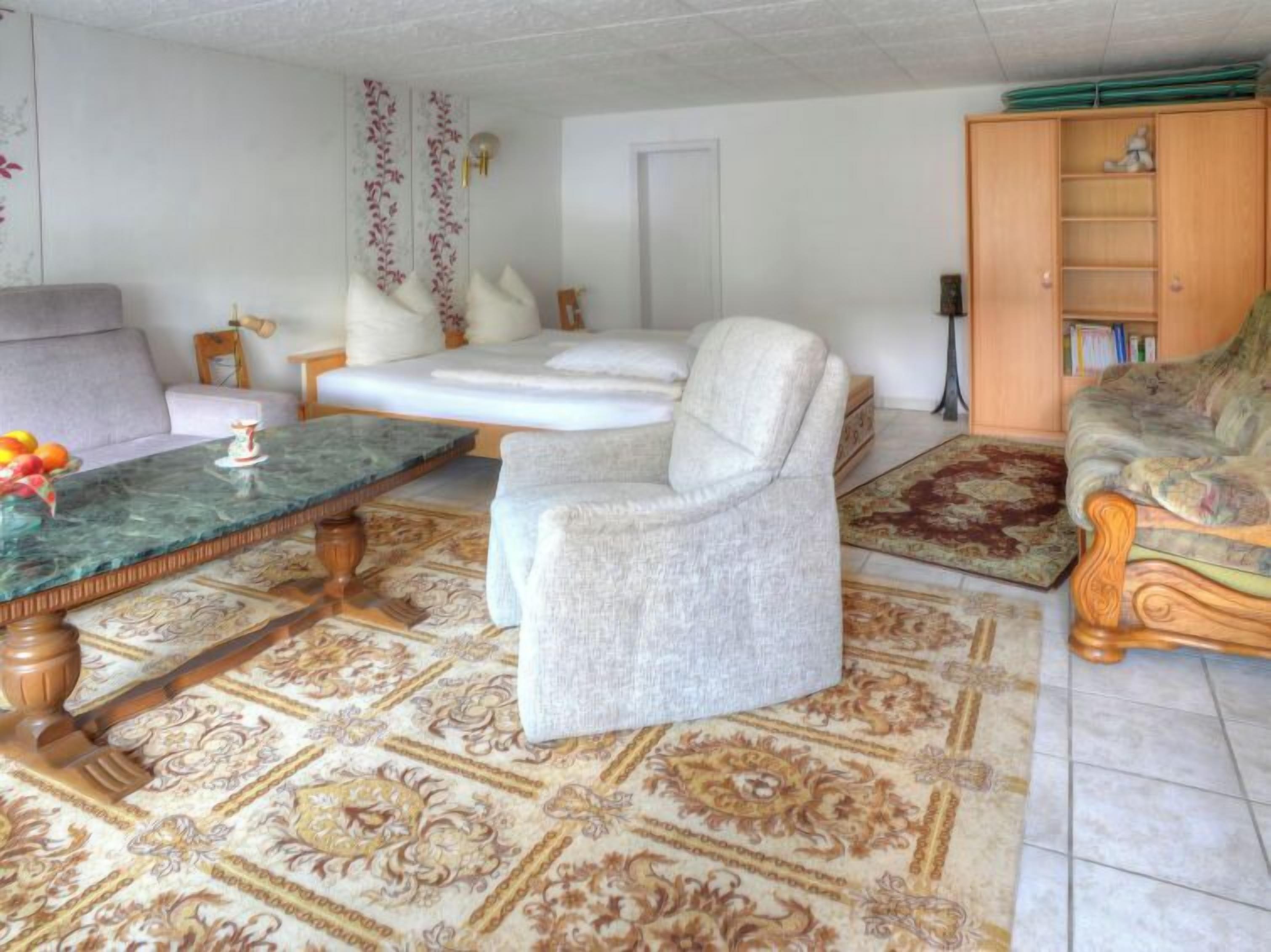 A living room with a sofa, armchairs, a coffee table, and a bookshelf.