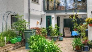 A courtyard with potted plants, a chair, and a table set up for outdoor dining. - Am Dohlenberg + Steintisch by Interhome (Schwalenberg)