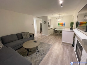 Relax in this stylish living space with a dark grey sofa, round coffee table, and dining area.