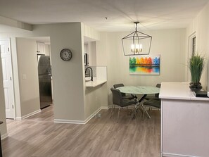A modern kitchen with a dining area, a clock, and a colorful painting on the wall. - Stoney Creek Northstar 20 (Whistler)