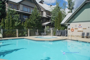 Relax by the resort's pool surrounded by a deck with lounge chairs and lush greenery.