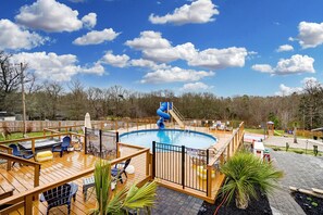A pool area with a slide, deck chairs, and a fenced pool. - Affordable Fun House (Rock Hill)