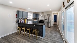 A modern kitchen with a central island, bar stools, and stainless steel appliances.