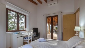 Ein Schlafzimmer mit Bett, Schreibtisch, Stuhl, Fernseher und Blick ins Freie.