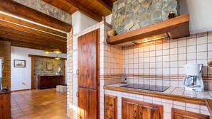 A kitchen with a stone wall, wooden cabinets, and a coffee maker. - Apartment Casa Patricia Nerja with Mountain View, Pool (Nerja)