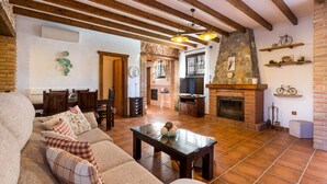 A living room with a sofa, a coffee table, a fireplace, and a stone wall. - Apartment Casa Patricia Nerja with Mountain View, Pool (Nerja)