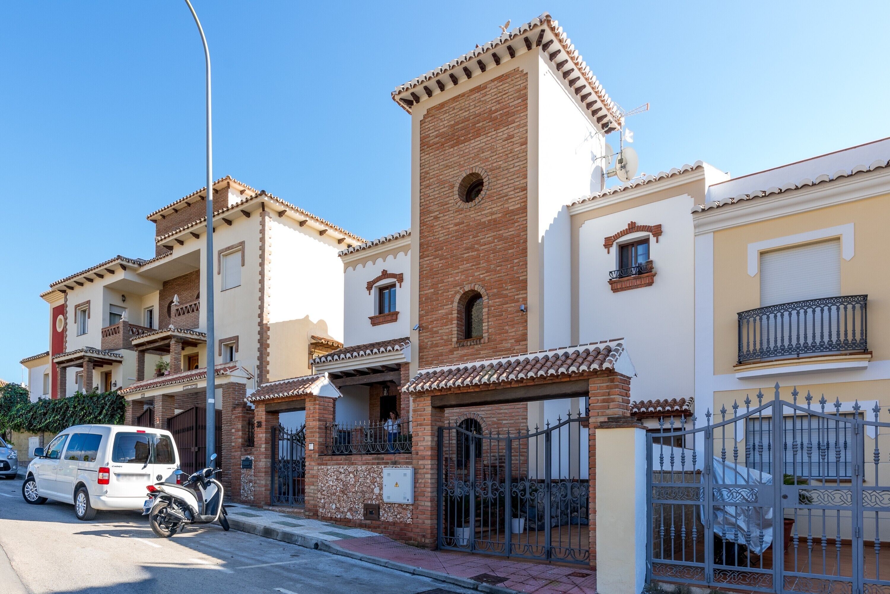 A residential building with a central tower, balconies, and a gated entrance.