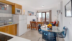 Une cuisine moderne avec des meubles en bois, un four à micro-ondes et un coin repas comprenant une table et des chaises en verre.