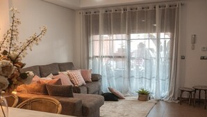 A living room with a sofa, cushions, a coffee table, a dining table, chairs, a rug, and a window with sheer curtains. - House "Amazing Duplex - 30m from the beach" with Sea View, Terrace, A/C & Wi-Fi (San Juan de los Terreros)