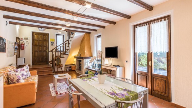 Ein gemütliches Wohnzimmer mit einer Couch, einem Esstisch, einem Kamin und einer Treppe zu einem anderen Raum.