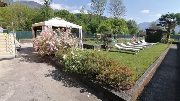 A garden with a tent, a pathway, and a pool area with lounge chairs.