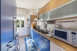 A modern kitchen with a microwave, sink, and wooden cabinets. - Casa Vacanza Elena: Family Paradise with Garden, Private Parking, Pet-Friendly, Val Grande View (Santino VB)