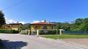 A yellow building with a red roof, a gated entrance, and a paved driveway.