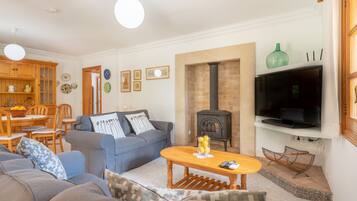 A living room with a sofa, coffee table, TV, fireplace, and dining area.