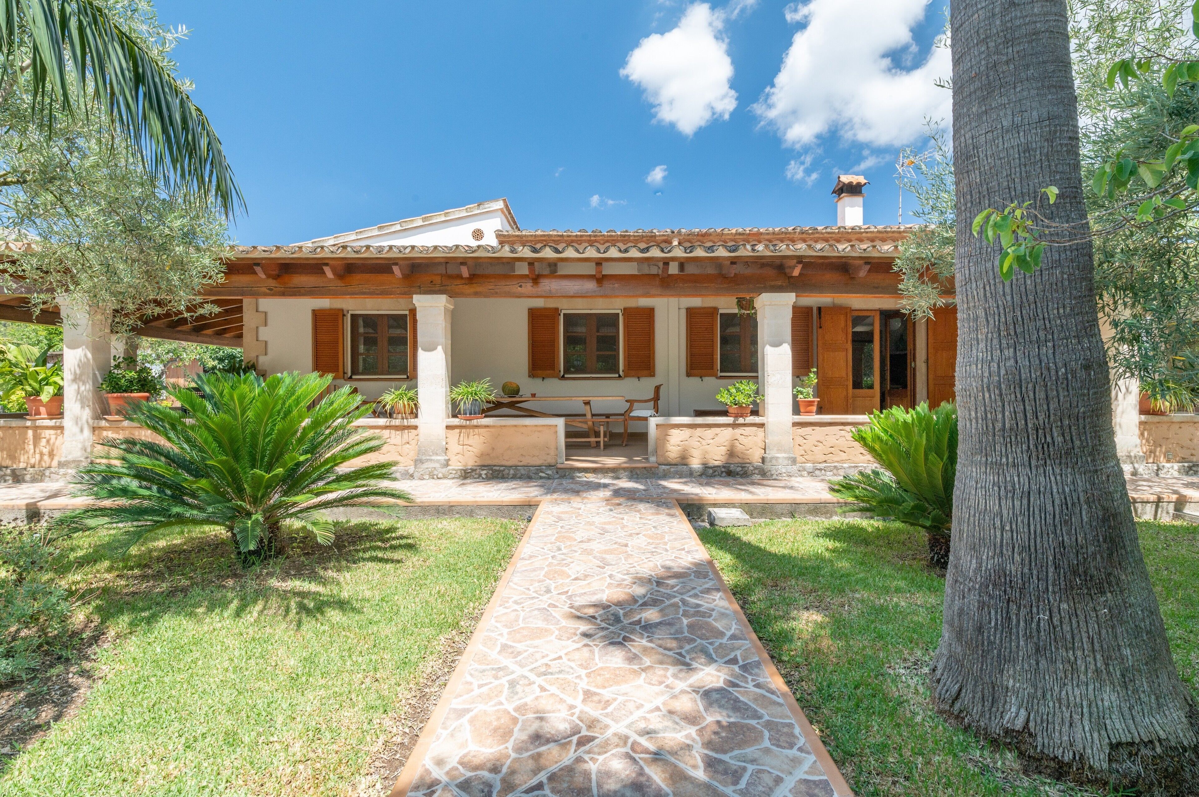 A house with a patio, a stone pathway, and potted plants.