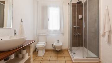Ein Badezimmer mit einem großen Waschbecken, Toilette, Bidet und einer Duschkabine.