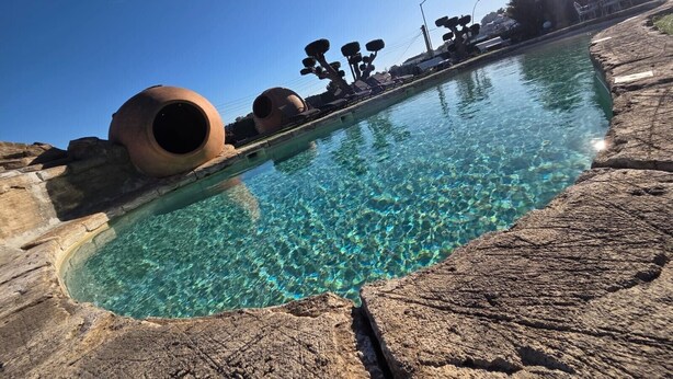 A clear pool with rock edges and large cylindrical structures. - Pet-Friendly Villa Masía Can Trabal with Mountain View, Pool, Jacuzzi, Wi-Fi, A/C, Terrace & Garden (Olèrdola)