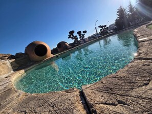 A clear pool with rock edges and large cylindrical structures.