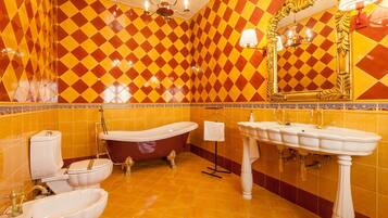 Een badkamer met een zwart-wit geruite vloer, een bad, twee wastafels en een toilet.