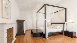 A four-poster canopy bed with a white canopy, a fireplace, and a framed artwork on the wall. - Pet-Friendly Villa Masía Can Trabal with Mountain View, Pool, Jacuzzi, Wi-Fi, A/C, Terrace & Garden (Olèrdola)