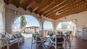 An outdoor patio with wicker furniture, a round table, and a pergola structure. - Pet-Friendly Villa Masía Can Trabal with Mountain View, Pool, Jacuzzi, Wi-Fi, A/C, Terrace & Garden (Olèrdola)