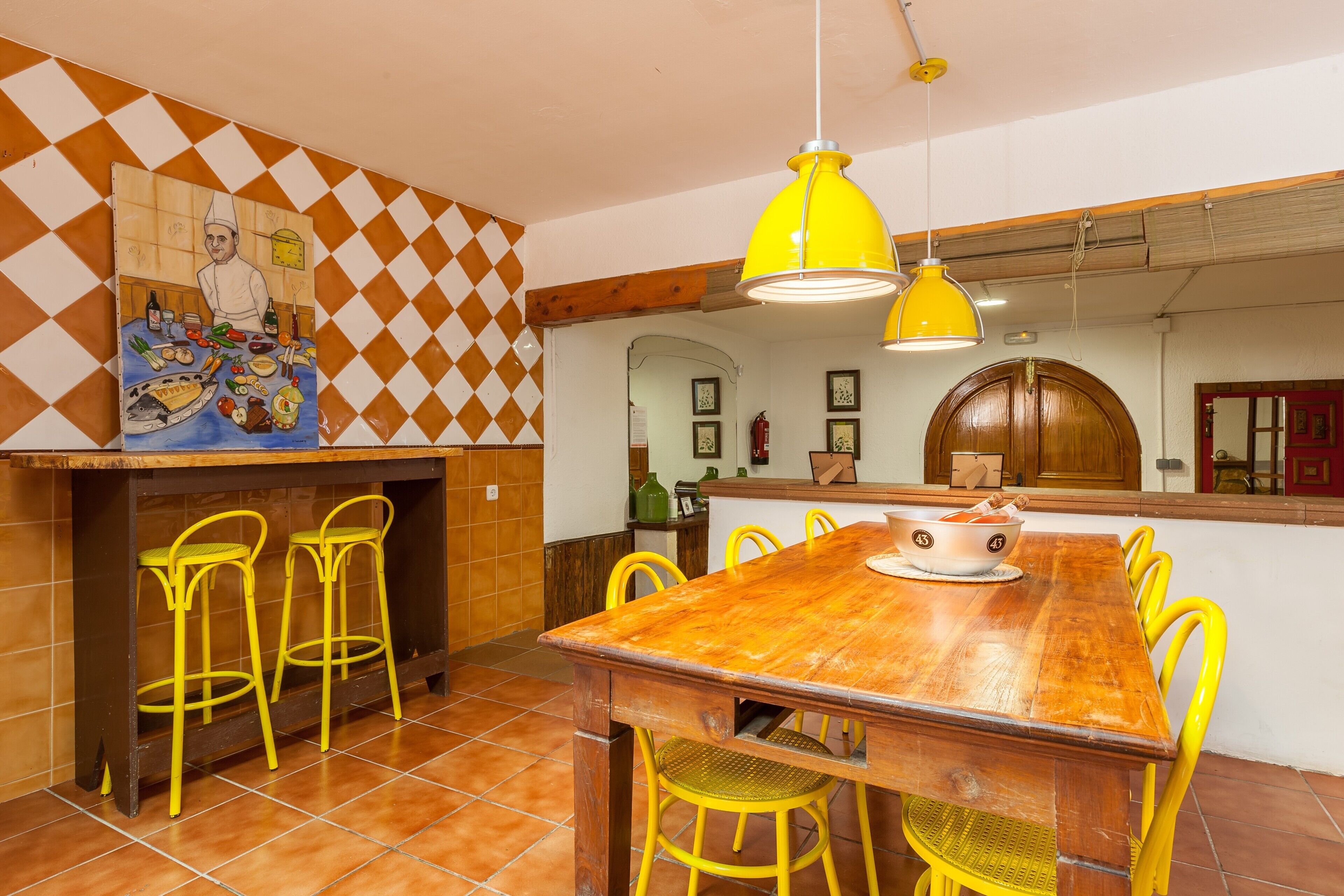 Un comedor con una mesa de madera, sillas amarillas y una lámpara colgante amarilla.
