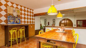 Un comedor con una mesa de madera, sillas amarillas y una lámpara colgante amarilla.