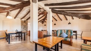 Un intérieur rustique avec des poutres apparentes, un mur en pierre et une table en bois accompagnée de chaises.
