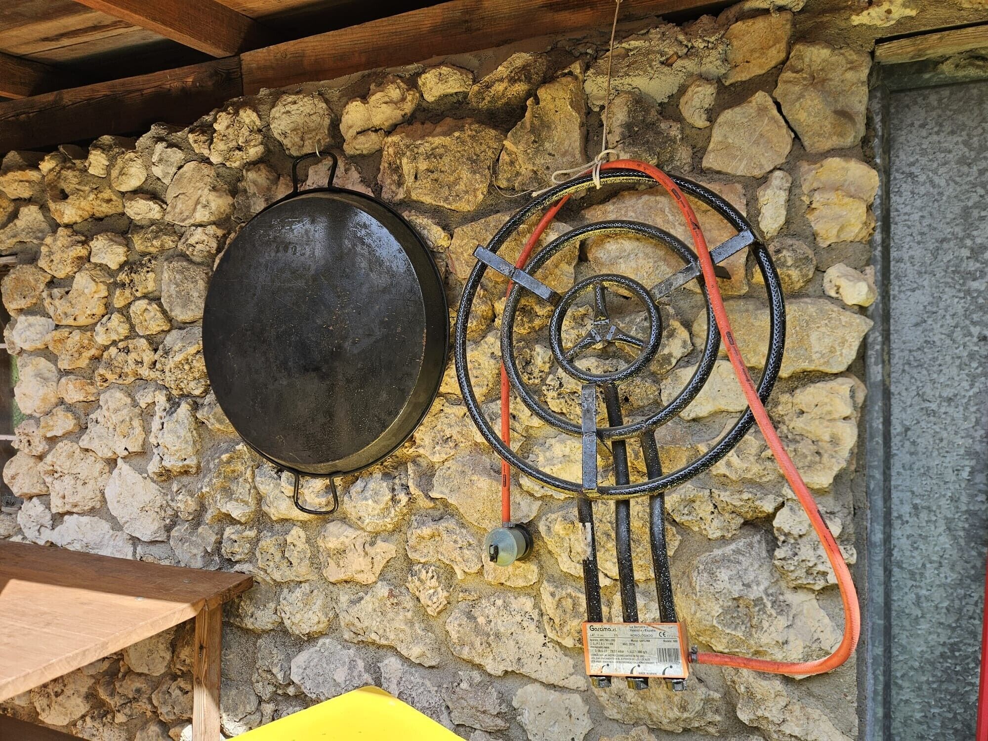 Un muro de piedra con una olla metálica y una manguera.