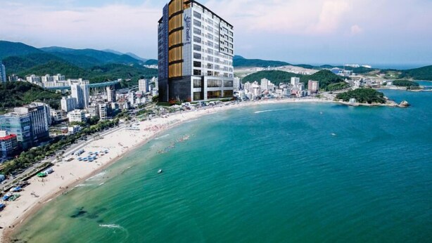 Un hotel moderno de gran altura cerca de una playa con aguas turquesas cristalinas.