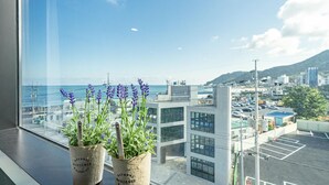 Vista desde una ventana con plantas de lavanda, con vistas a un paisaje urbano con edificios modernos y cielo despejado.
