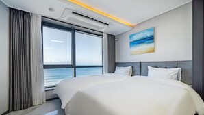 Habitación de hotel con una cama grande, vista al mar y diseño moderno.