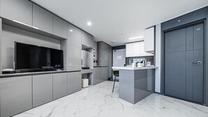 Una cocina moderna con armarios grises, suelo de mármol y una puerta grande de color gris.