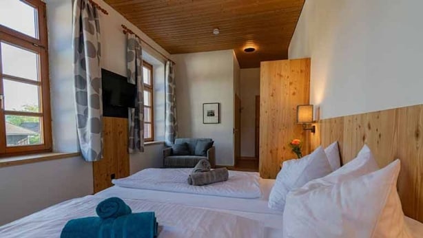 Habitación de hotel con dos camas, televisión, sofá y techo de madera.