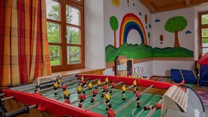 Ein Tischkicker in einem Raum mit großen Fenstern, einer Wandmalerei mit Regenbogen, Bäumen und einer Heißluftballon.