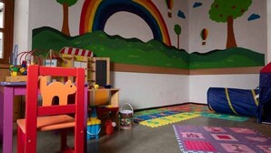 Ein Kinderzimmer mit einer farbenfrohen Wandmalerei, einem Spieltisch und einem Stuhl.