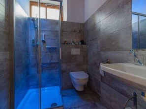 A bathroom with a glass-enclosed shower, a toilet, and a sink with a mirror.