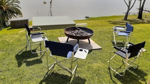 Un área de estar al aire libre con una mesa, sillas, una parrilla y vistas a un lago.