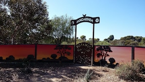 Una puerta con un letrero que dice "Panganda" y una cerca decorativa con siluetas de árboles.