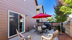 A deck with outdoor furniture, a red umbrella, and a sliding glass door.