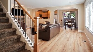 A spacious living area with a wooden staircase, a leather sofa, and a dining table.