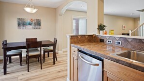 A modern kitchen with a wooden dining table, built-in dishwasher, and a large island with a sink.