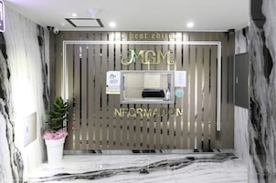 Un área de recepción con pared de mármol, una planta en maceta y un cartel que dice "MGM Information".