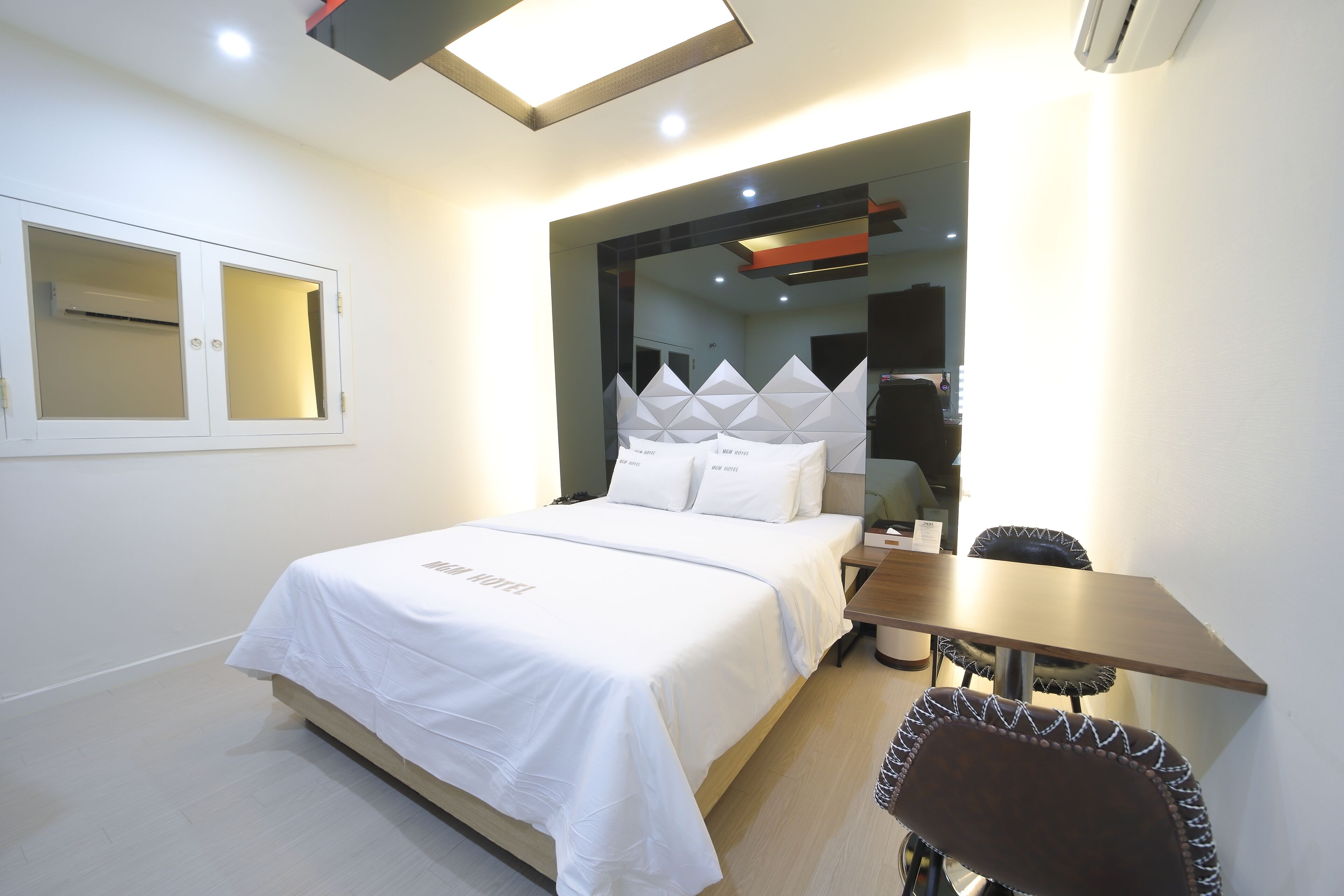 Una habitación de hotel moderna con una cama bien hecha, una mesita y una silla.