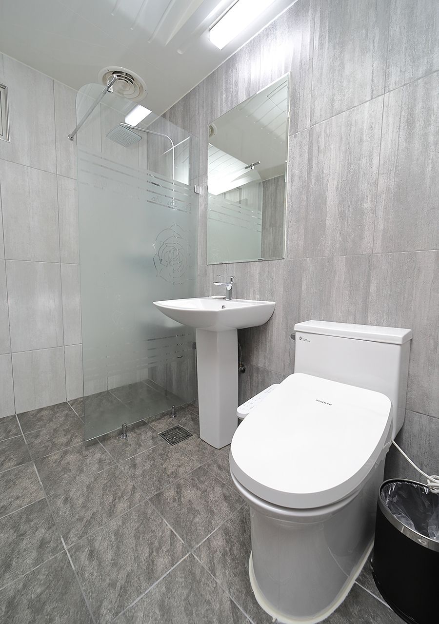 Un baño moderno con ducha, lavamanos, inodoro y un espejo grande.