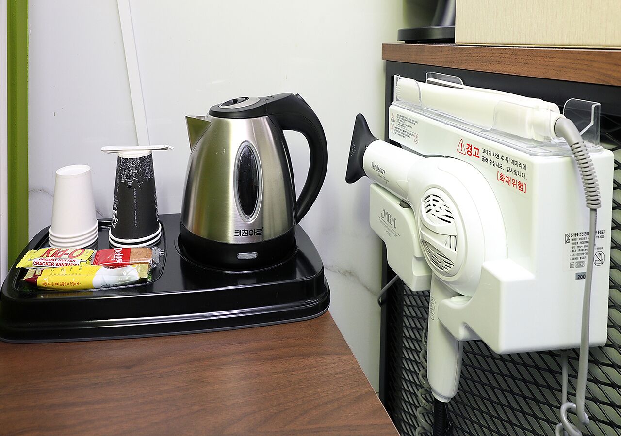 Un coin cuisine équipé d’une bouilloire, d’une machine à café et d’un plateau contenant un sandwich et une tasse.