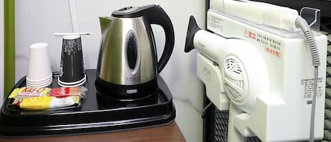 Un coin cuisine équipé d’une bouilloire, d’une machine à café et d’un plateau contenant un sandwich et une tasse.