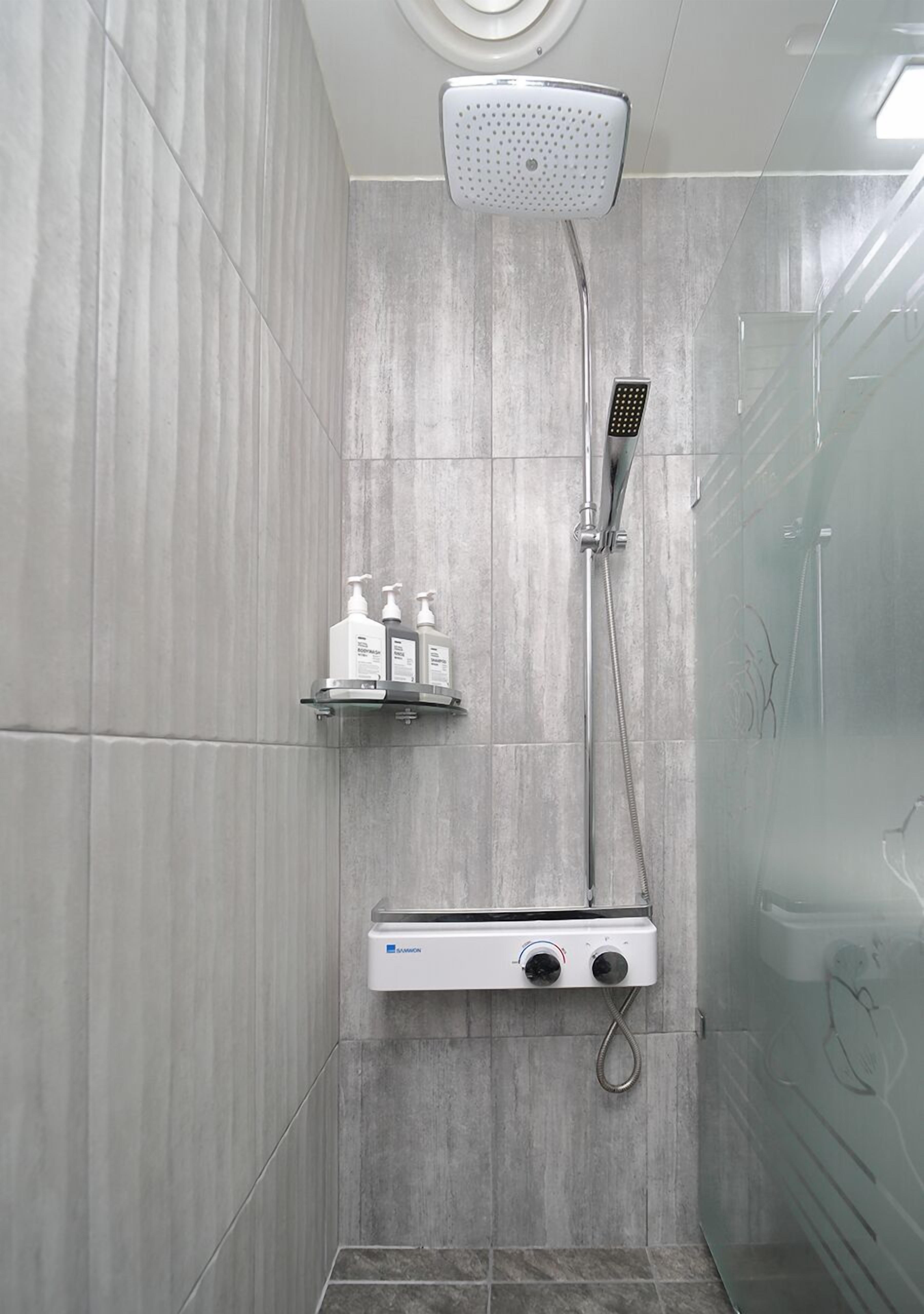 A modern shower with a handheld showerhead, a wall-mounted faucet, and a control panel.